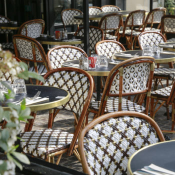 Terrasse parisienne avec chaises en rotin et guéridons